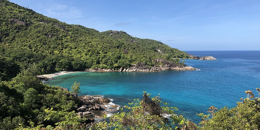 Anse Major, a peaceful beach surrounded by lush vegetation, stunning waters under blue sky