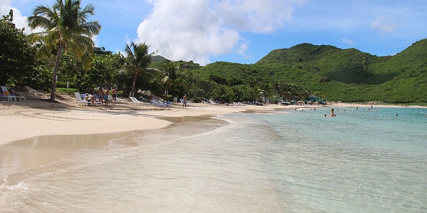 A quiet, peaceful beach surrounded by lush hills and crystal-clear waters.