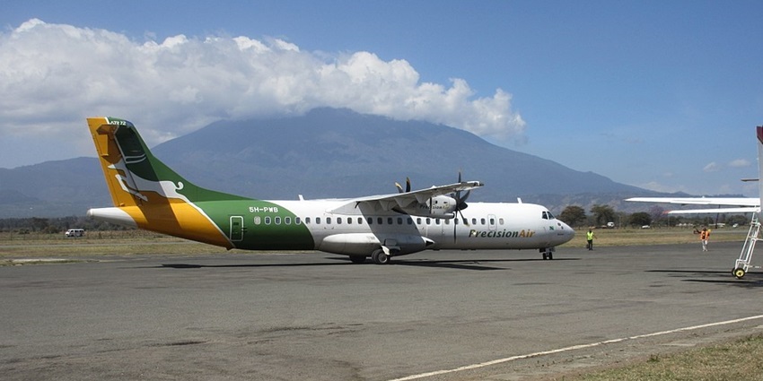 Arusha airport runway with a white, green, yellow colour flight and Mount Meru in background