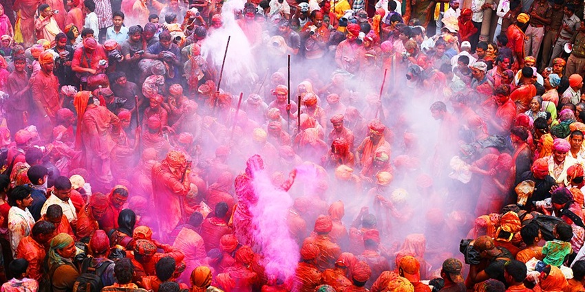 Women dressed in vibrant sarees wait with sticks in their hands during Lathmar Holi.