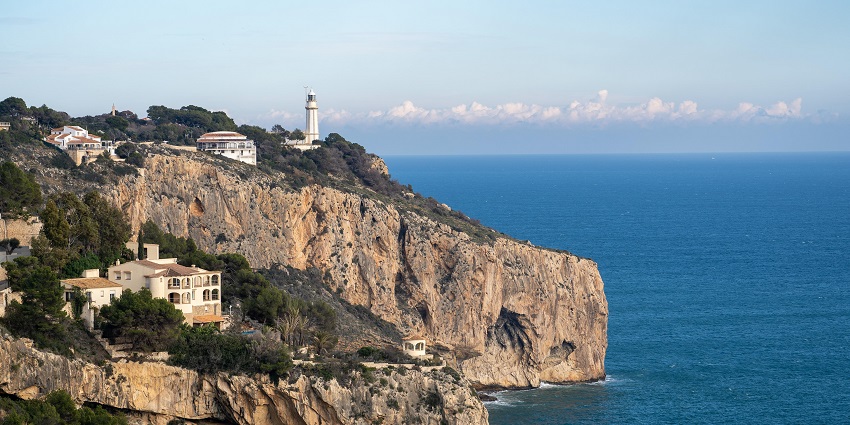 Dramatic cliffs with swaying palm trees seen at Bagni della Regina Giovanna Beach