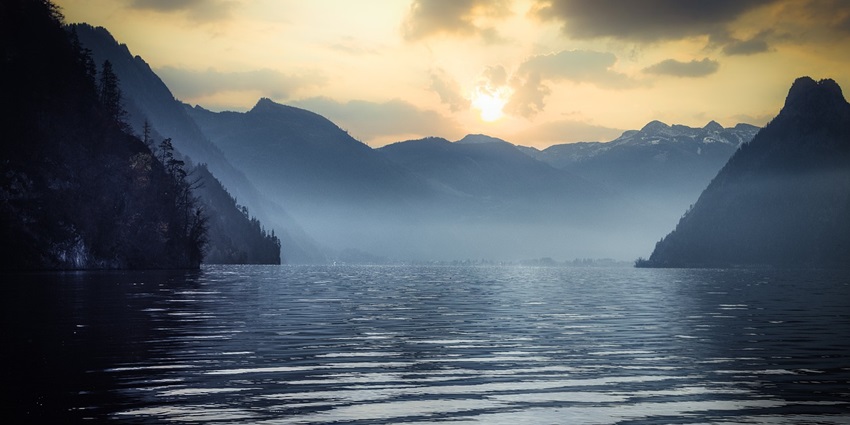 An image of a serene lake surrounded by mountain peaks at sunset, resembling Blasmand lake