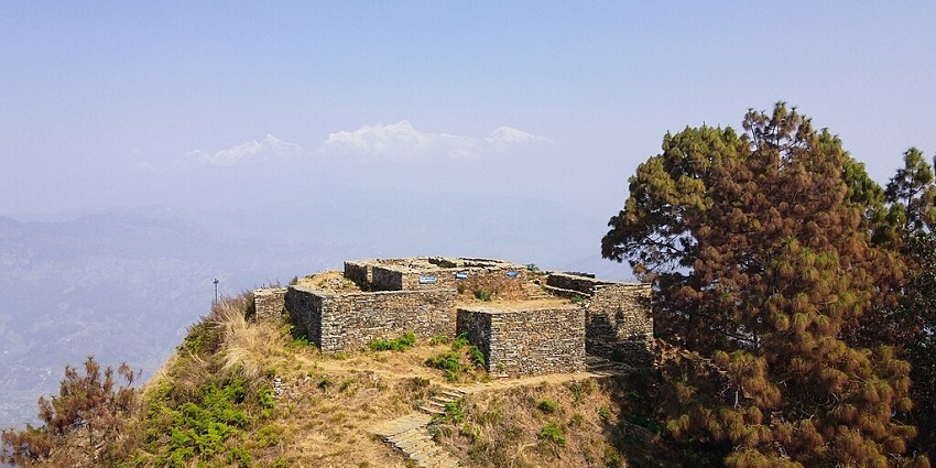 Image of fort ruins on top of the hill surrounded by lush greenery covered mountains