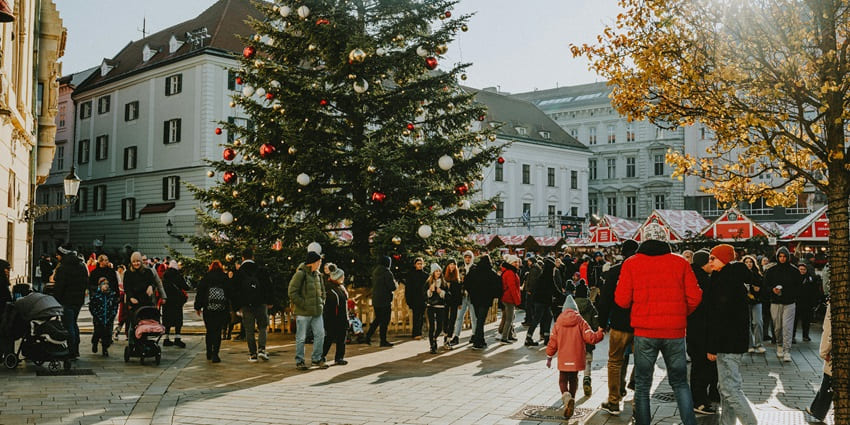 An image of a crowded Christmas market with a large decorated tree, festive stalls and people enjoying, similar to the Christmas celebrations in Bangalore.