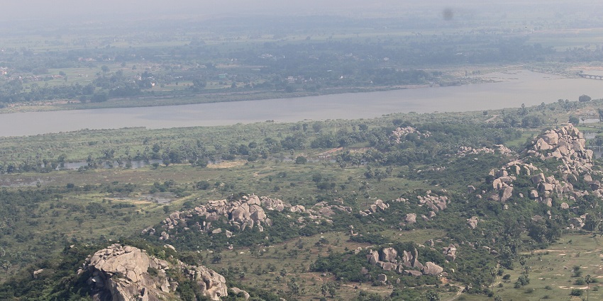 The aerial view of the Barabar Caves surrounded by mountains and a river.
