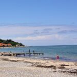 An image of a beautiful beach in Denmark with clear blue waters and sandy shores.