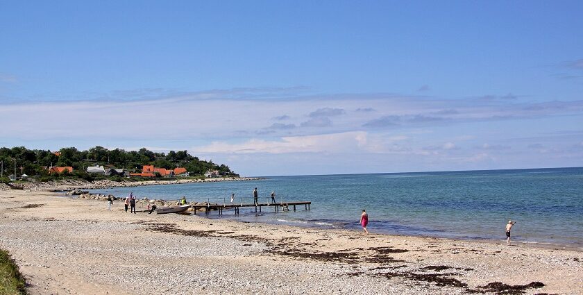 An image of a beautiful beach in Denmark with clear blue waters and sandy shores.