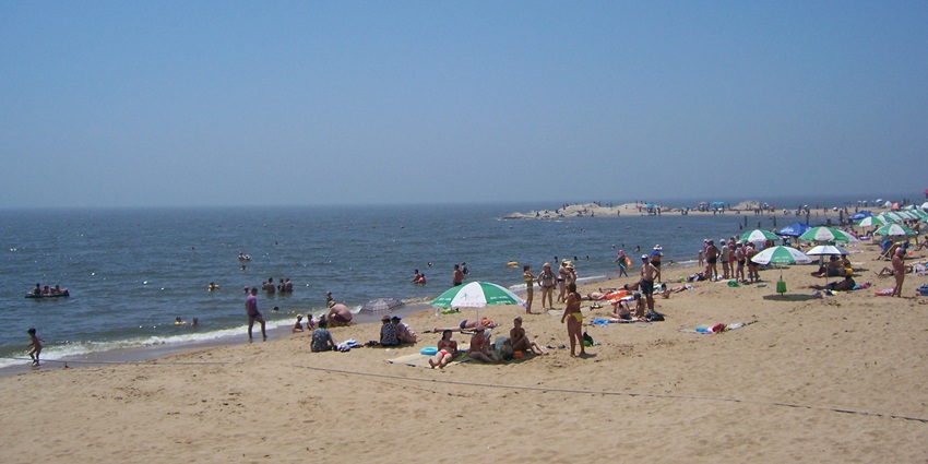 An image of Beidaihe Beach in china with a clear blue sky, calm water, and distant hills.