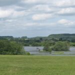 View of the Great Lake of the UK showing clear waters, small trees in between and green grass around