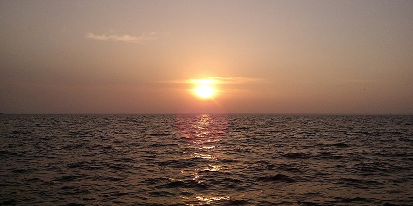 An image of a scenic sunset over Vembanad Lake, creating a magical atmosphere.