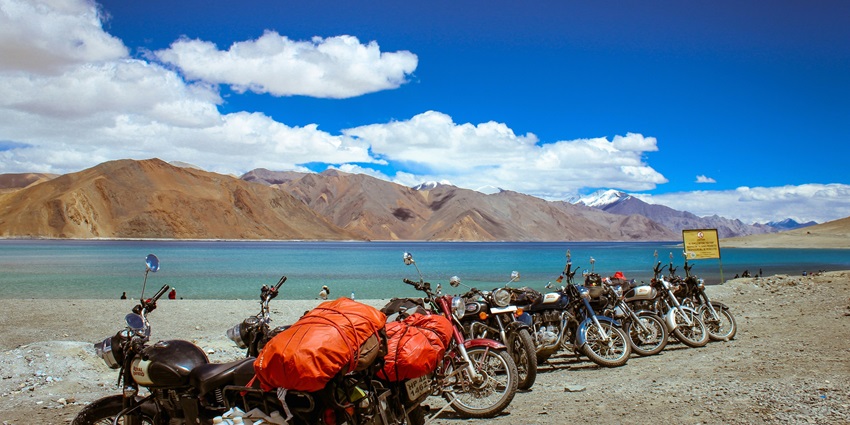 Image of assorted colour motorcycle parked beside Pangong Tso Lake during day time