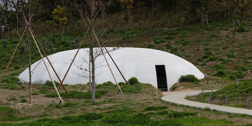 Teshima Art Museum, a white, dome-shaped building, sits nestled into a green hillside