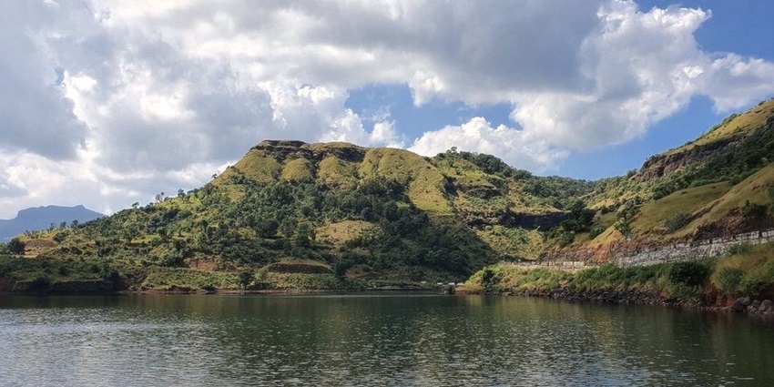 Bhavali dam lake with the road leading to the dam, large water body and distant hills.