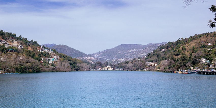 A Panoramic view of Bhimtal Lake with lush hills and Aquarium Island Café in sight.
