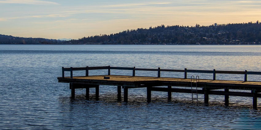 A picture of a tranquil lake at sunset with a serene dock view.