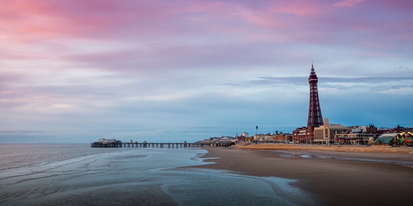 A lively beach with an amusement park, iconic tower views and lively atmosphere.