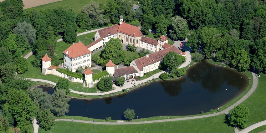 Aerial southeast view of Blutenburg Castle surrounded by lush greenery and water