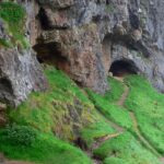 Entrance to the Bone Caves in Scotland, surrounded by rugged limestone cliffs and hills