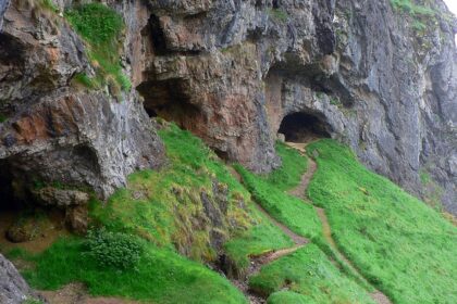 Entrance to the Bone Caves in Scotland, surrounded by rugged limestone cliffs and hills