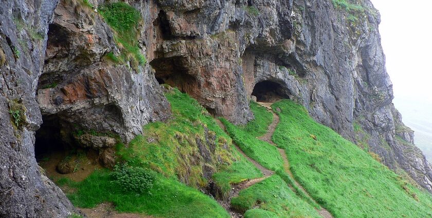 Entrance to the Bone Caves in Scotland, surrounded by rugged limestone cliffs and hills