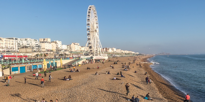 A vibrant pebble beach with an iconic pier and lively atmosphere at Brighton Beach.