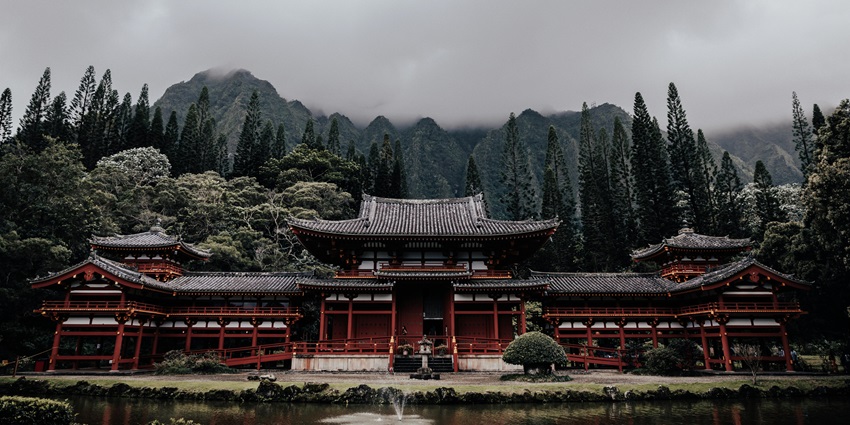 A scenic view of Byodo-in’s Phoenix Hall, its golden phoenix shining above a calm pond.