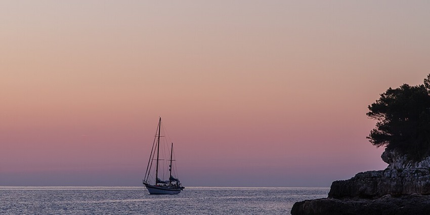 Picturesque view of pink sunset and a ship sailing at the beach during sunset
