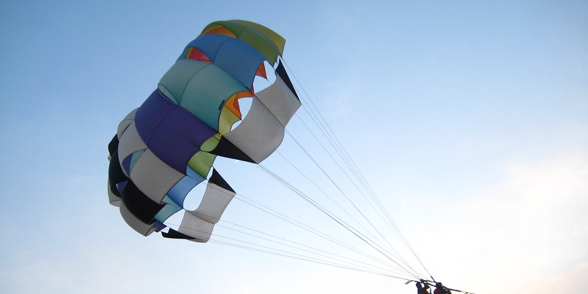 Two people enjoying parasailing above Calangute Beach in North Goa, India.