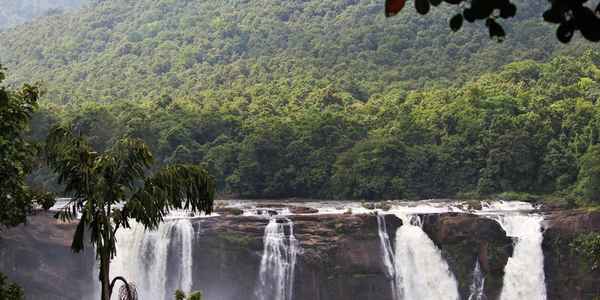 Stunning waterfall surrounded by lush greenery and rocky cliffs.