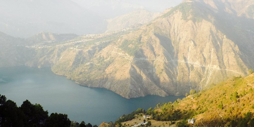 Chamera Lake from the top with misty weather, distant buildings and big rocky mountains