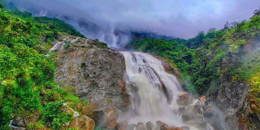 An image showing Cherrapunji, Meghalaya, with vast landscapes and cloud-covered hills.