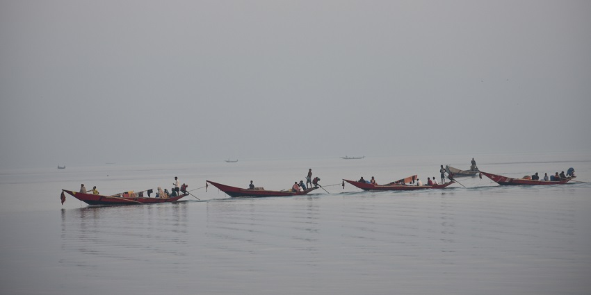Chilika Lake in Odisha with people sitting on the four boats on the lake in line