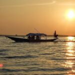 Silhouette of a boat with people in it and reflection of sunsetting on the Chilika Lake