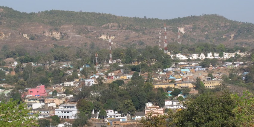 A lush green hill station in Central India with city establishments surrounding the hill.