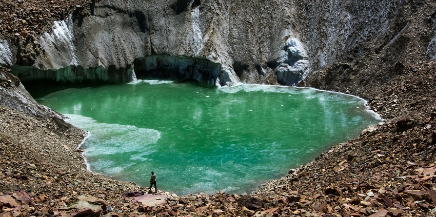 A Glacial pool with a bright green water body surrounded by rocks resembling Chumnai Lake