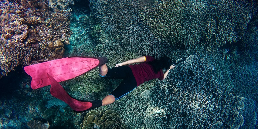 A woman with snorkel gear, lying on the water, similar to the waters of Cinque Island.