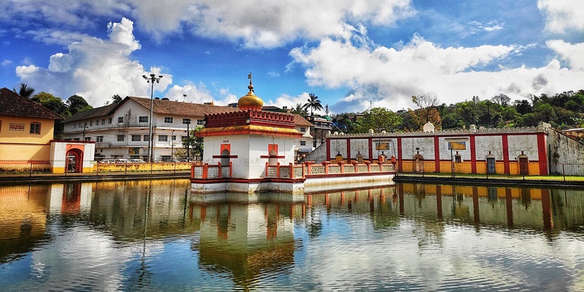 Omkareshwara Temple in Madikeri, Coorg—architectural fusion amid reflective water tank.