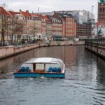 An image of Copenhagen's waterfront with boats and historical buildings in the background.