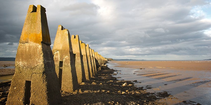 The Cramond Beach shore is seen with wartime defences and remnants of history by the sunset.