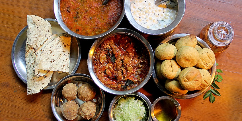 A plate of delicious Dal Baati Churma served with other delicious side dishes.