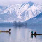 Dal Lake in January with people on boats in the lake and snow-covered mountains in back