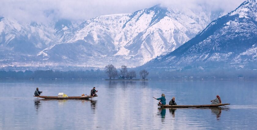 Dal Lake in January with people on boats in the lake and snow-covered mountains in back