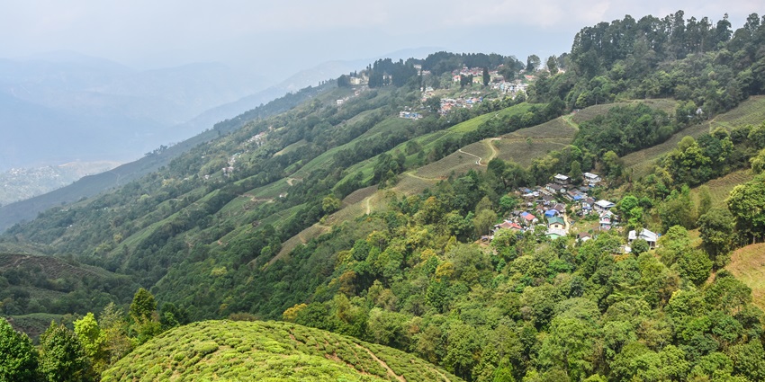 Scenic landscape of Darjeeling with hills, houses, and mist-covered mountains.