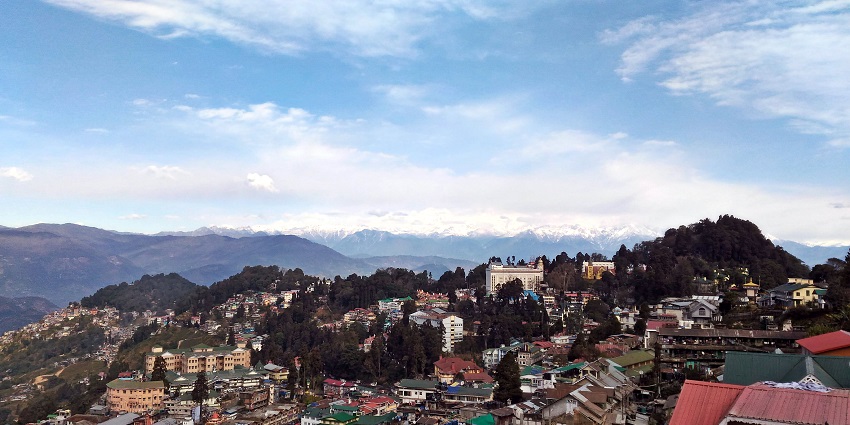 An image of the Darjeeling Himalayan Railway with a backdrop of snow-covered peaks.