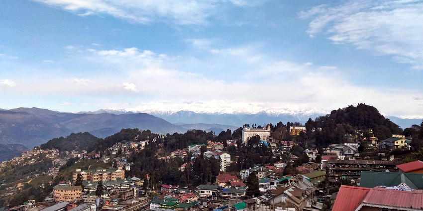 An image of the Darjeeling Himalayan Railway with a backdrop of snow-covered peaks.