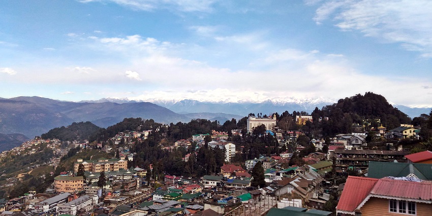 A serene image of Darjeeling's vibrant town with a backdrop of snow-covered peaks.