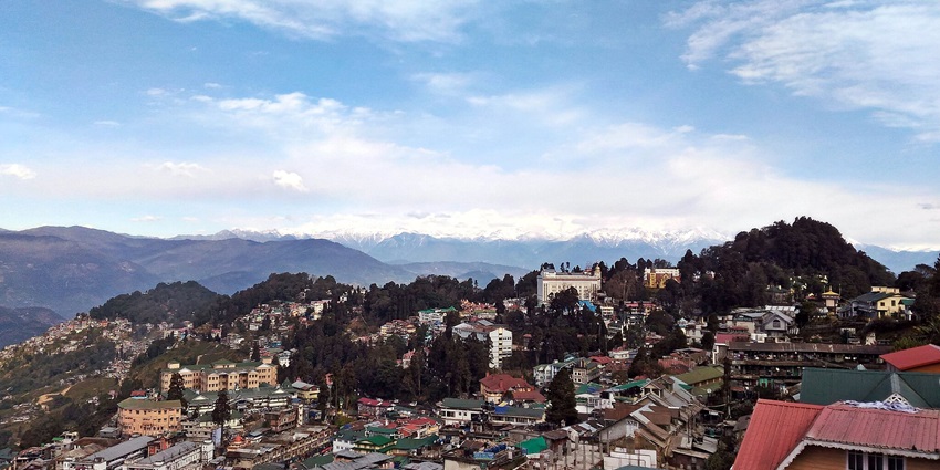 An image of the Darjeeling Himalayan Railway with a backdrop of snow-covered peaks.