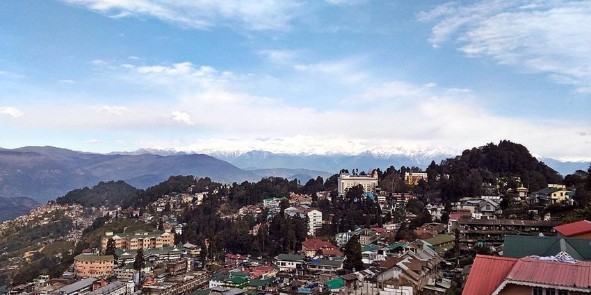 An image of the Darjeeling Himalayan Railway with a backdrop of snow-covered peaks.