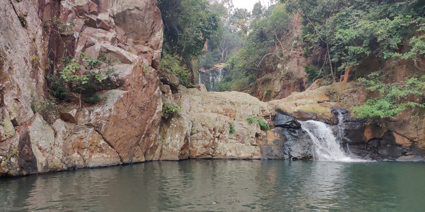 Sambalpur waterfall flowing down into the small lake surrounded by rocks and trees