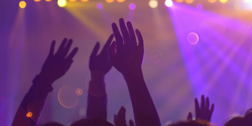 An image of silhouetted hands raised in the air, showcasing the nightlife in India.